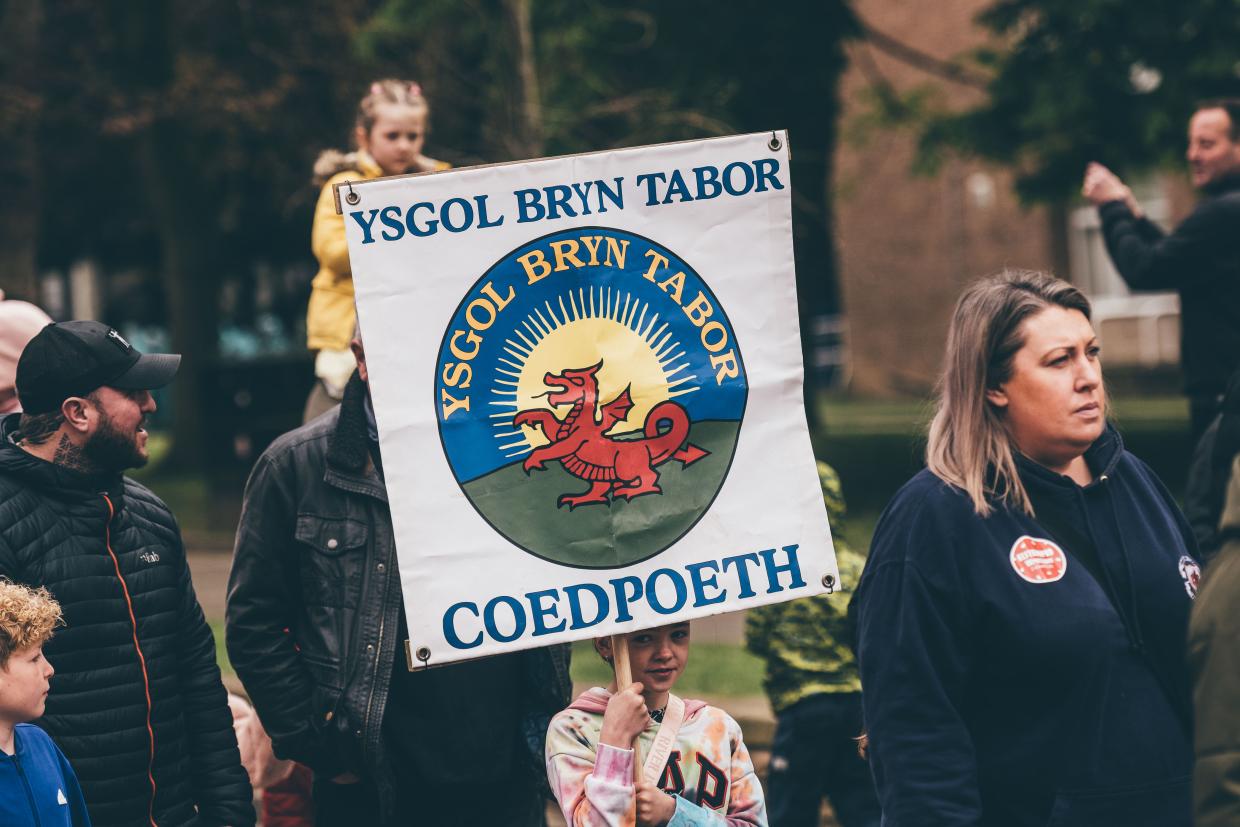 Baner liwgar un o'r ysgolion yn gorymdeithio yn ystod Cyhoeddi Eisteddfod 2025