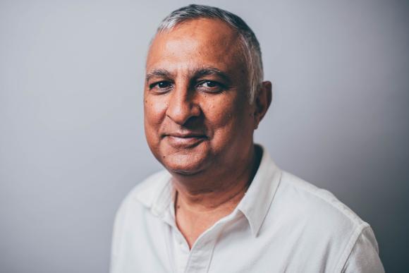 Person wearing a white collared shirt standing against a plain background
