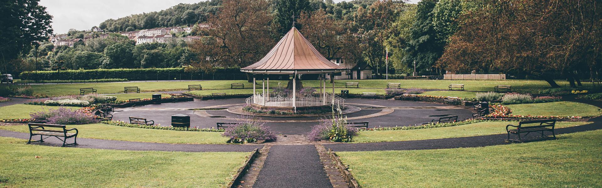 Bandstand in the heart of Ynysangharad Park, Pontypridd, surrounded by seasonal flower beds and a lush sunken area for an audience