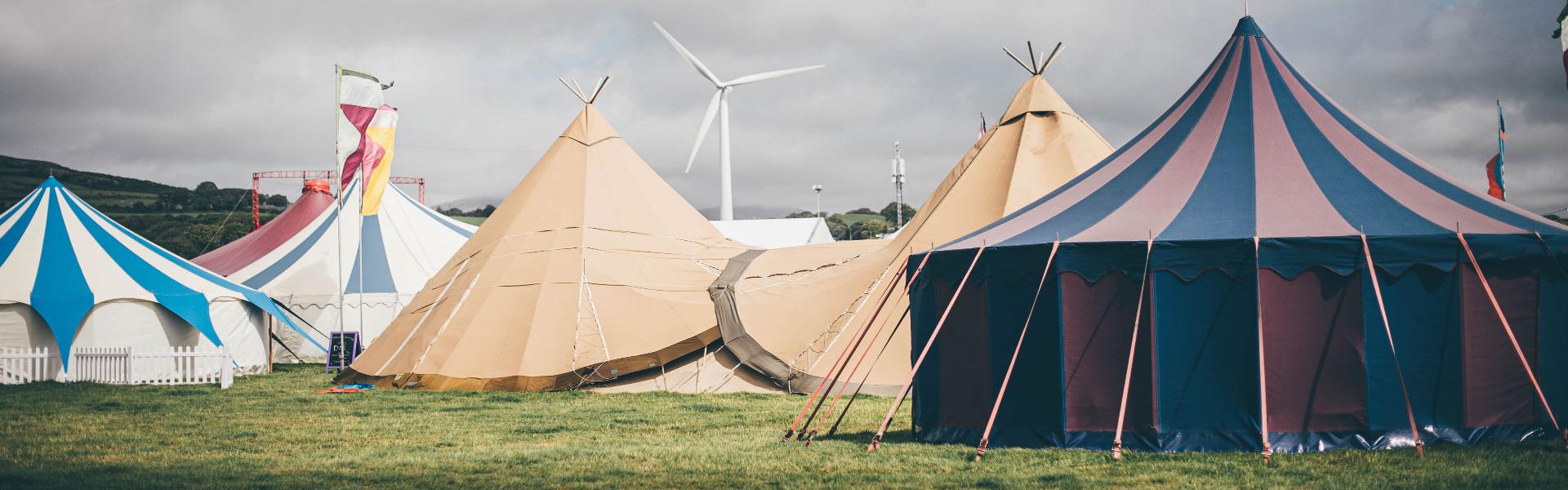 A collection of different tents in a field under a grey sky