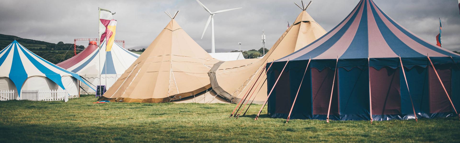 A collection of different tents in a field under a grey sky