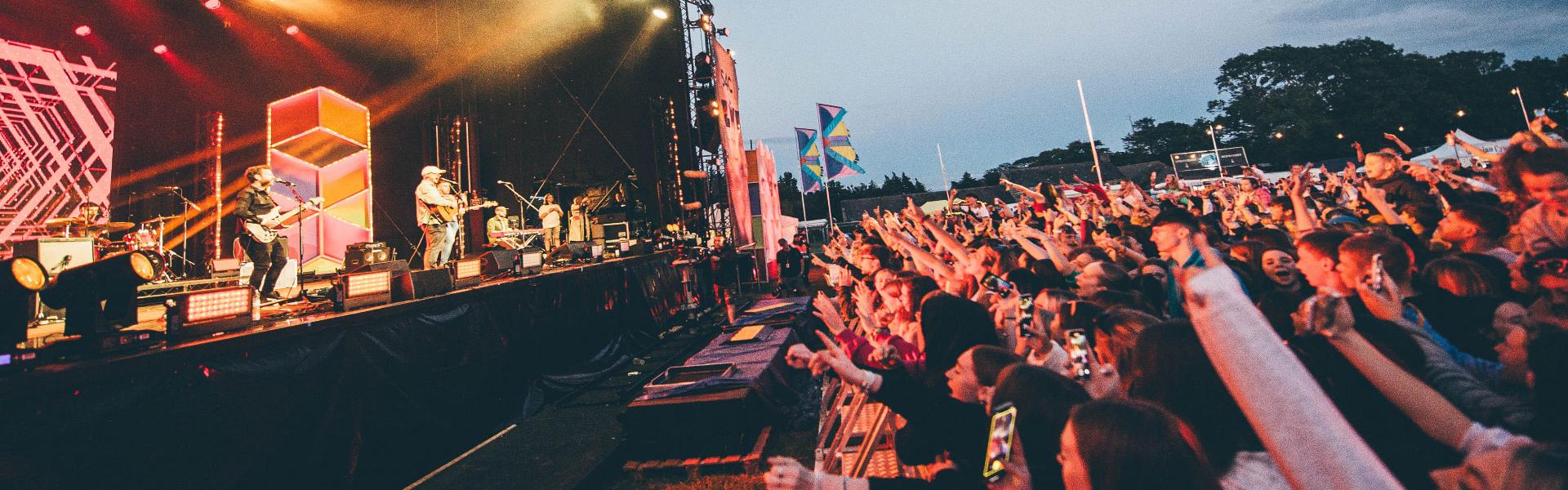 Band on a big stage and audience watching at night with bright lights