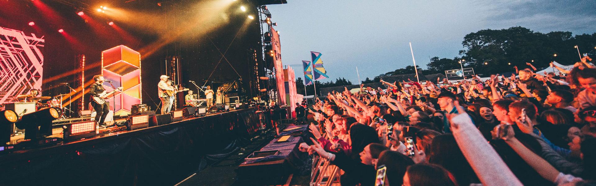 Band on a big stage and audience watching at night with bright lights