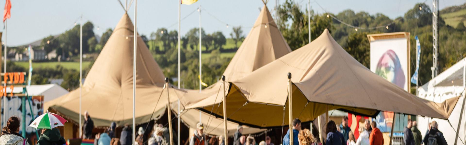 Brown teepees with flags around them. Maes B Cafe