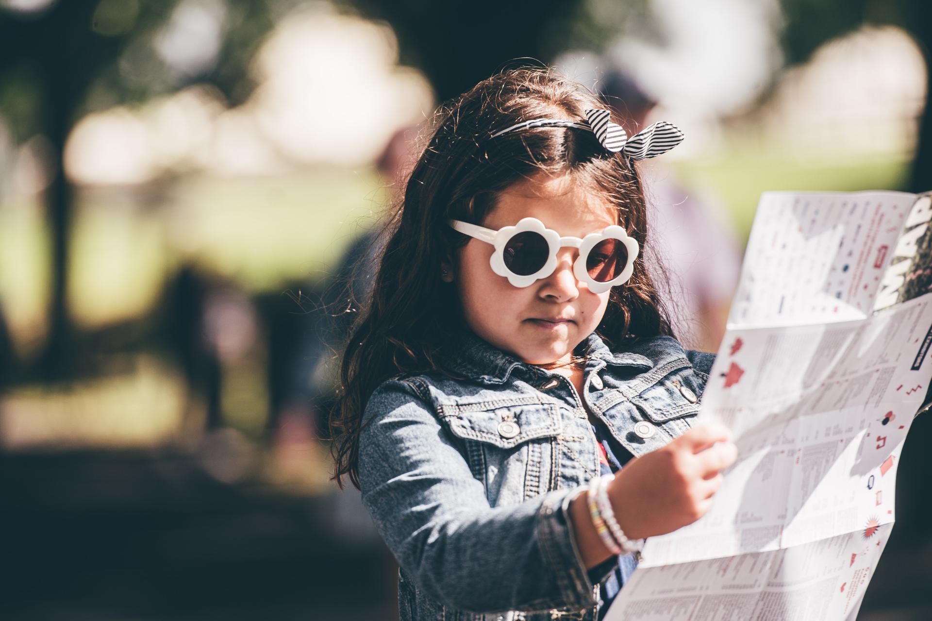 Young girl with sunglasses looking reading the Eisteddfod's leaflet