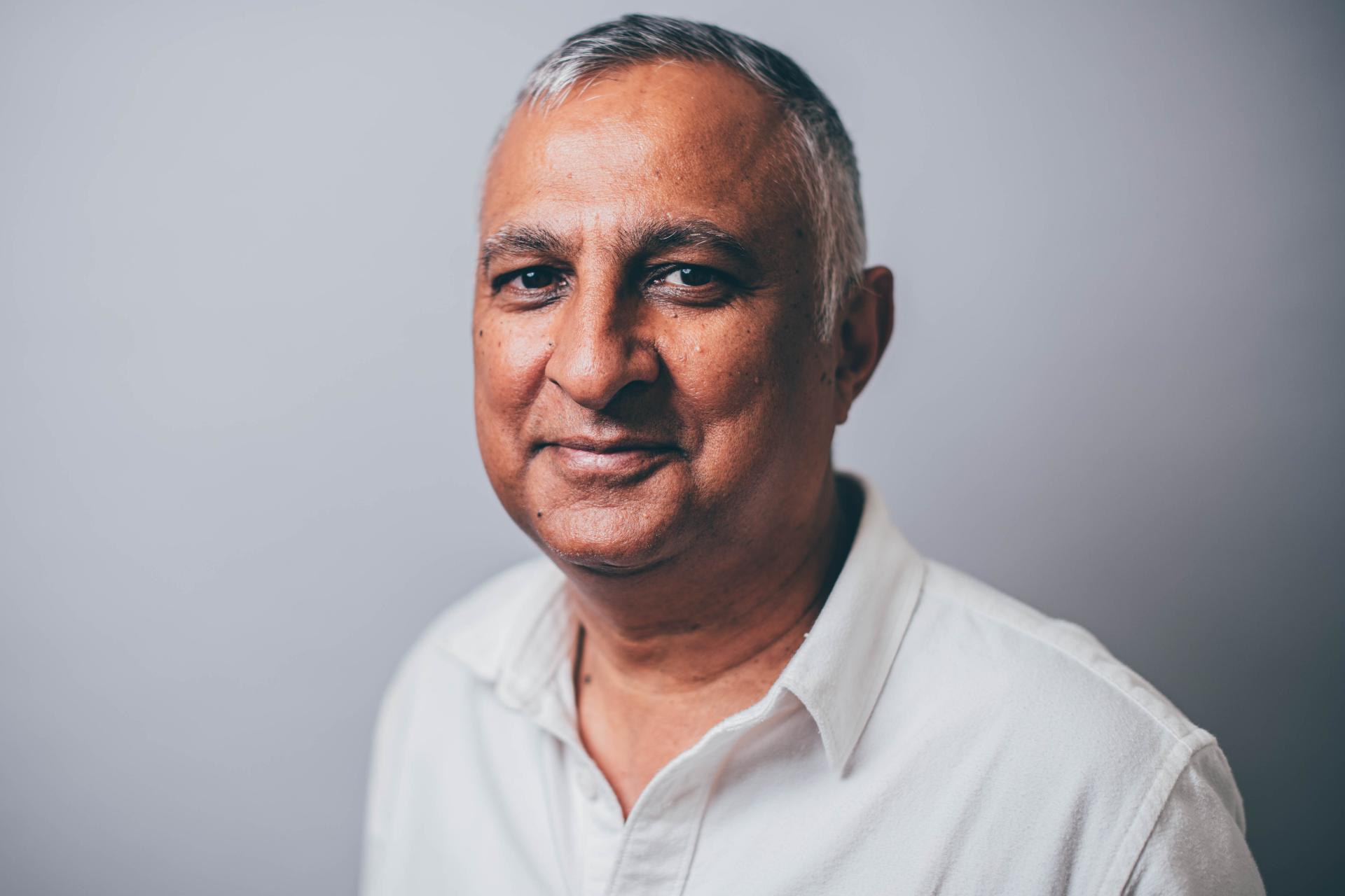Person wearing a white collared shirt standing against a plain background
